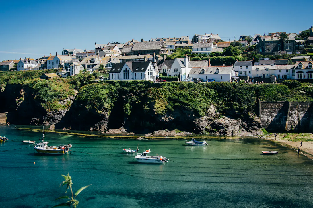 Cornish harbour with fishing boats below white cottages on the cliffside